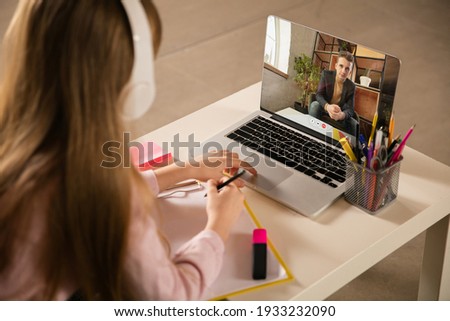 Little girl studying by group video call, use video conference with teacher, listening to online course. Using headphones, notebook. Easy, comfortable usage concept, education, online, childhood.