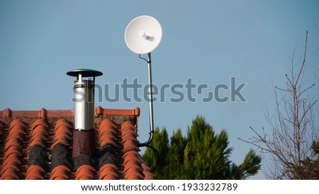 Little white parabolic antenna on rooftop