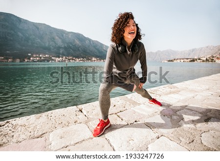 Athletic young woman with curly hair doing exercises on the beach