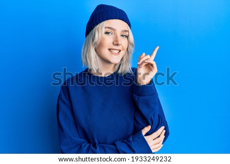 Young blonde girl wearing casual clothes smiling happy pointing with hand and finger to the side 