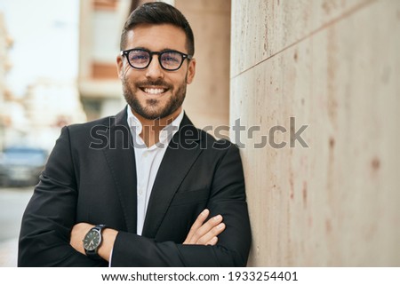 Young hispanic businessman with arms crossed smiling happy at the city. Royalty-Free Stock Photo #1933254401