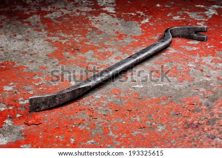 An old crowbar on a red background 