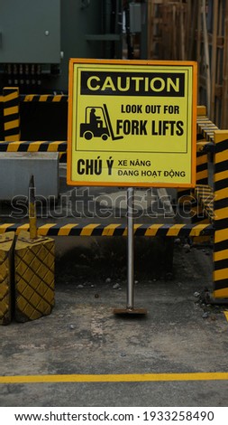 A warning sign of forklift area in both english and vietnamese "Chú ý xe nâng hoạt động" (caution look out for forklift) Royalty-Free Stock Photo #1933258490