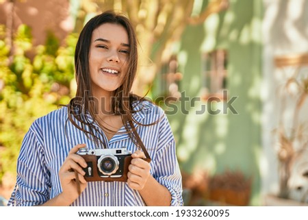 Young hispanic tourist girl smiling happy using camera at the park.