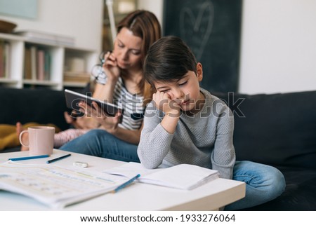mother helping her son to do homework. he is tired and exhausted