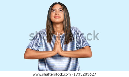Young latin girl wearing casual clothes begging and praying with hands together with hope expression on face very emotional and worried. begging. 