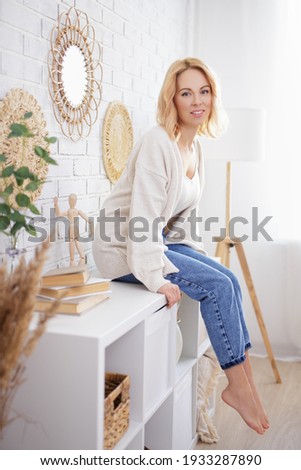 portrait of young beautiful woman sitting on shelf at home
