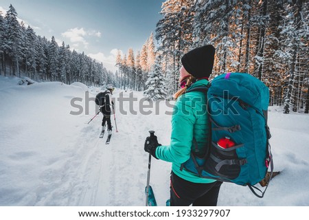 Mountaineer backcountry ski walking ski alpinist in the mountains. Ski touring in alpine landscape with snowy trees. Adventure winter sport. Royalty-Free Stock Photo #1933297907