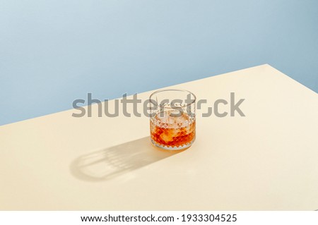 Glass with Whiskey and Ice Cube on Table on Blue Background. Modern Isometric Style. Creative Concept Royalty-Free Stock Photo #1933304525