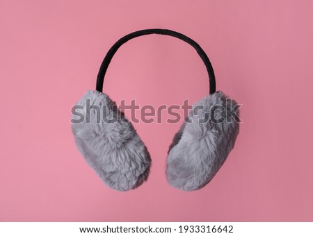 Fluffy earmuffs on pink background. Stylish winter accessory Royalty-Free Stock Photo #1933316642
