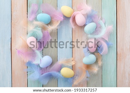 Happy easter concept. Frame with colorful Easter eggs and feathers on wooden background. Flat lay.