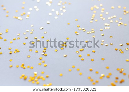 Golden shiny stars glitter or confetti on gray background