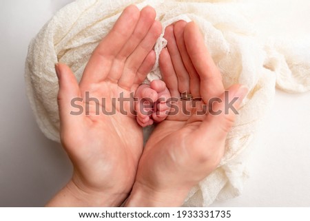 baby feet in the hands of the mother. parents ' wedding rings on the toes of a newborn Royalty-Free Stock Photo #1933331735