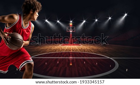 Young African American boy with basketball in the middle of the stadium ready to go to the basket