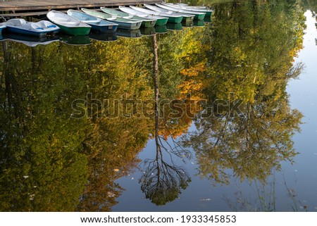 A pond in an autumn park, a bright reflection of trees in the water. The boats are moored.