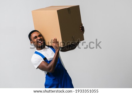courier with a paper box, a young African American man in a blue jumpsuit and a white T-shirt holding craft paper boxes for sending. Isolated on a white background. The concept of delivery, mail, ship
