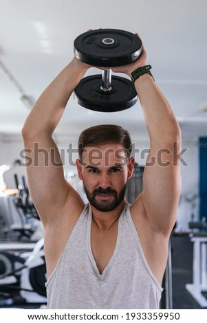 Man doing triceps with dumbbells on his back.