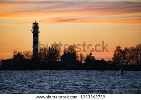 Seascape at sunset. Lighthouse on the coast. Royalty-Free Stock Photo #1933363739