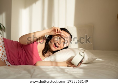 beautiful young woman waking up with an alarm clock 