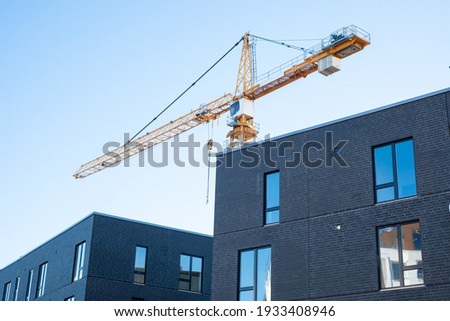 Crane working on a construction site. Building of new residential apartments. Real estate development in urban area in Northern Europe.
