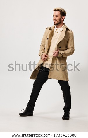 fashionable man in a beige coat trousers on a light background fashion trend of the season spring. High quality photo