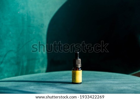 Massage or cosmetics oil bottles. Close up of cardamoms and essential oil on chair. High angle view of massage oil bottle on green background. Concept of healthy lifestyle and self care. Copy space