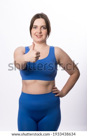 Young plus size woman in sports uniform shows "class" on a white background. close-up.