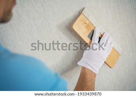 Canvas Textured Vinyl Wallpaper Installation with Squeegee Tool. Apartment Remodeling. Royalty-Free Stock Photo #1933439870