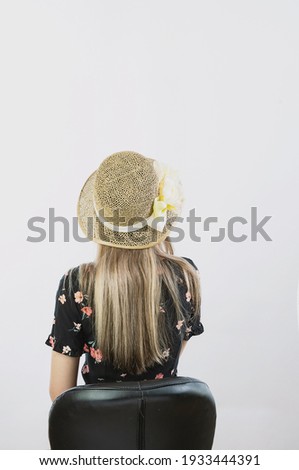 girl in a sundress and straw hat posing on a light, solid background