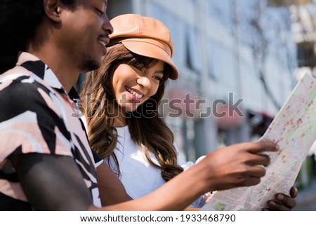 Young tourist couple looking at map outdoors. Royalty-Free Stock Photo #1933468790