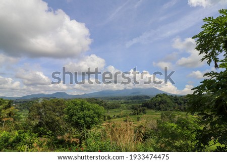 Tropical landscape in Bali Island. Blue and cloudy sky over hills on background.