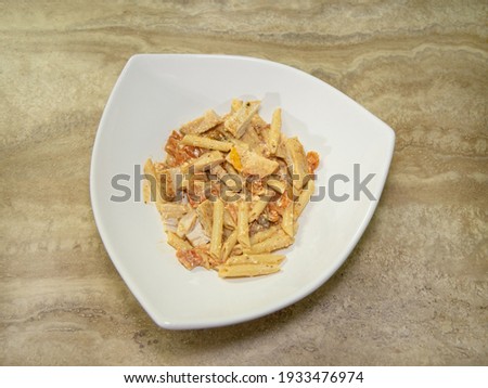 The viral baked feta cheese pasta sauce with penne pasta and chicken served on a white bowl. 
