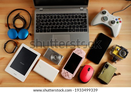 laptop computer with Smartphone and portable game consoles and ebook reader and many electronic gadgets on wooden background.Top view. Royalty-Free Stock Photo #1933499339
