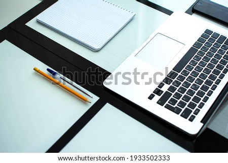 top side view. copy space. horizontal. Black mobile phone, notebook, pen, pencil lie on a black and white glass table.successful communication. cyberspace. working. freelance. design. simplicity.