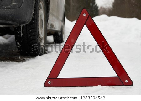 Car with a breakdown on snowy road. Winter driving,  warning triangle on a winter road