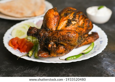 A plate of full thandoori chicken , Arabian spicy food tandoori whole chicken Bengaluru, India . Platter served with salads. Al Faham Charcoal Grilled Chicken .	
 Royalty-Free Stock Photo #1933520480