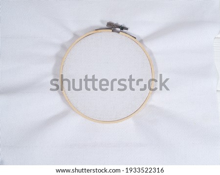 Embroidery hoop with white canvas on a white wooden background. Copy space. Top view.  Royalty-Free Stock Photo #1933522316