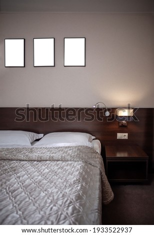 Interior of a comfortable hotel bedroom in the morning in luxury style. Big window. Black wooden photo frames mockup, interior decor