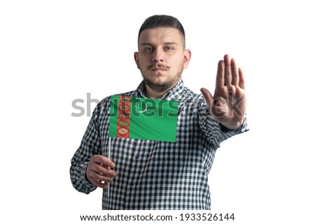 White guy holding a flag of Turkmenistan and with a serious face shows a hand stop sign isolated on a white background.