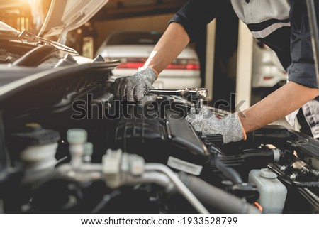 Automobile mechanic repairman hands repairing a car engine automotive workshop with a wrench, car service and maintenance,Repair service. Royalty-Free Stock Photo #1933528799