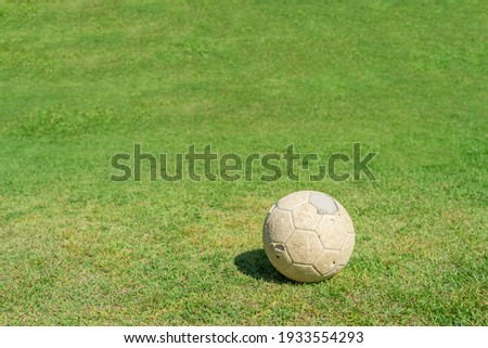 Old soccer ball on green grass of soccer field. Vintage football.