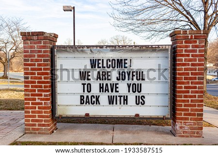 A large notice board in front of a public school in Maryland with a message to students who have been away due to pandemic pandemic. It says: welcome, we are joyful to have you back with us.