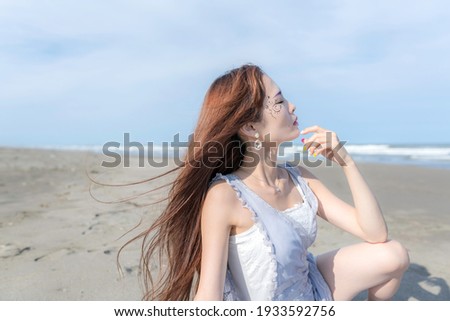 A picture of a woman sitting on the beach in the summer