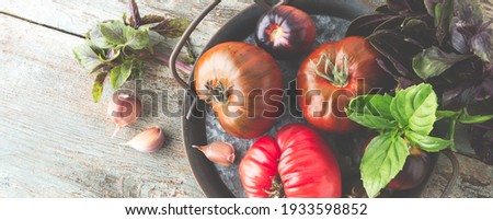 flat lay of tray with fresh organic tomatoes and fresh basil on wooden table