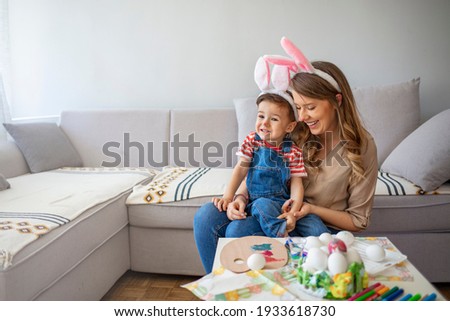 Happy son and mother preparing creative eggs. Mother and son painting Easter eggs. Easter fun and joy. Young mother teaching little son to dye Easter eggs