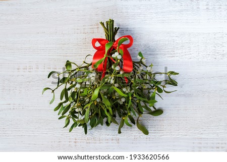 branches of evergreen white mistletoe with berries tied with a red ribbon on a white background. christmas concept