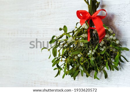 branches of evergreen white mistletoe with berries tied with a red ribbon on a white background. christmas concept