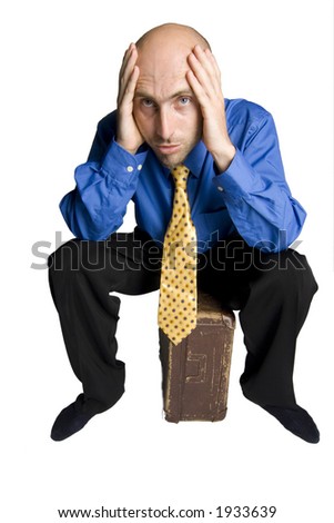 Young man in depression sitting on his suitcase
