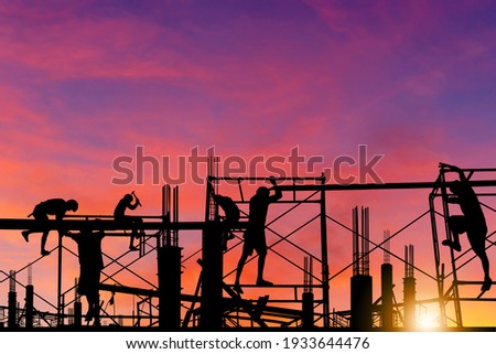 Silhouette of worker on building site, construction site at sunset in evening time. Royalty-Free Stock Photo #1933644476