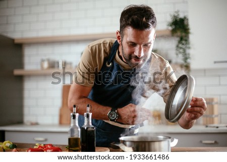 Handsome man preparing pasta in the kitchen. Guy cooking a tasty meal.	 Royalty-Free Stock Photo #1933661486